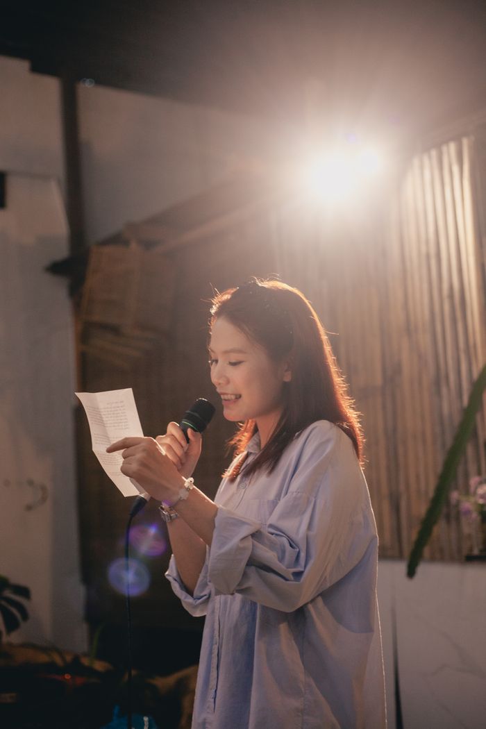 About A woman delivers a speech or performance under warm lighting indoors with natural decor.