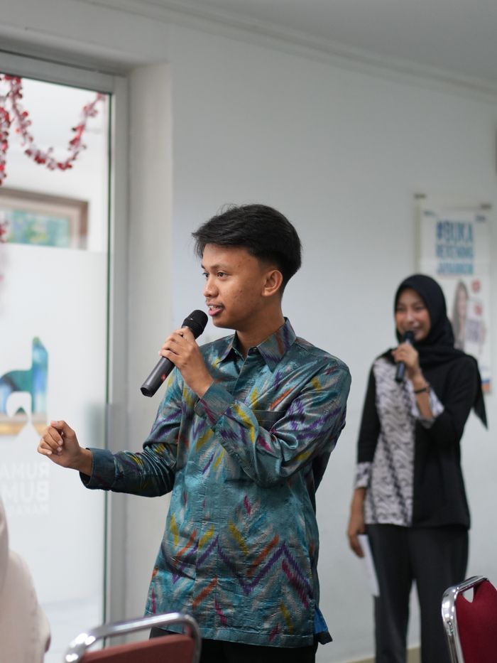 Service Two young adults speaking into microphones during an indoor seminar.